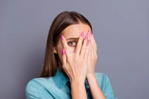 Woman closing face with palms isolated on gray background