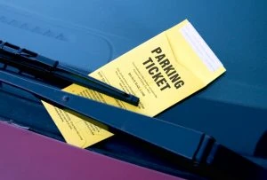 yellow parking ticket under a car windshield wiper