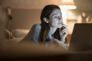 Woman laying down watching TV on her laptop
