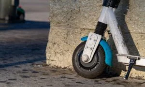 Shared electric scooter against a city wall.