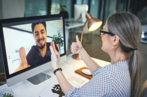 Shot of a young man showing thumbs up during an online meeting with a colleague