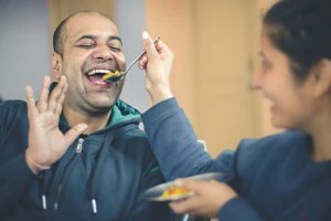 Woman feeding man with a spoon.