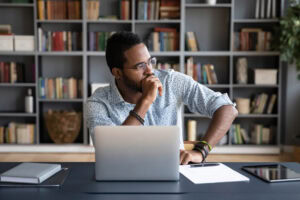 Black businessman sitting at workplace thinking over problem solution
