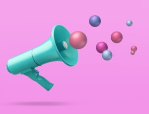 Megaphone on pink background with conceptual colourful balls spheres in air