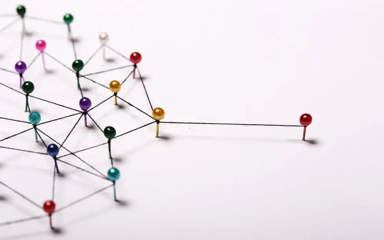 Stock photo with pins representing networking nodes and strings representing connections, with one main node outside the network