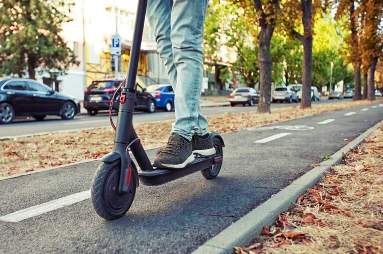 Stock photo of person on an electric scooter on a city sidewalk designated for bikes and scooters