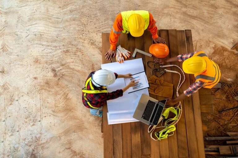 Stock photo of aerial shot of architect and builders standing around a wooden table