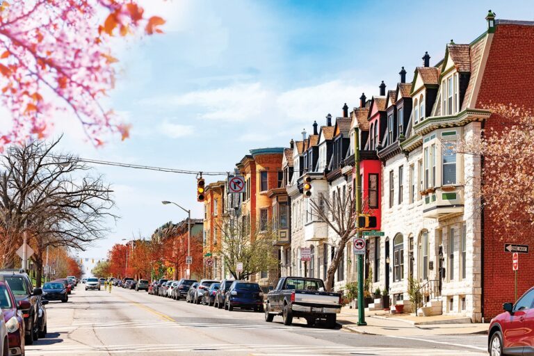 Colorful photo of a city street in autumn, lined with parked cars