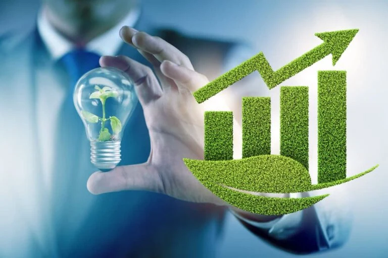 Green Economy growth concept, including a man holding a clear light bulb with a plant inside