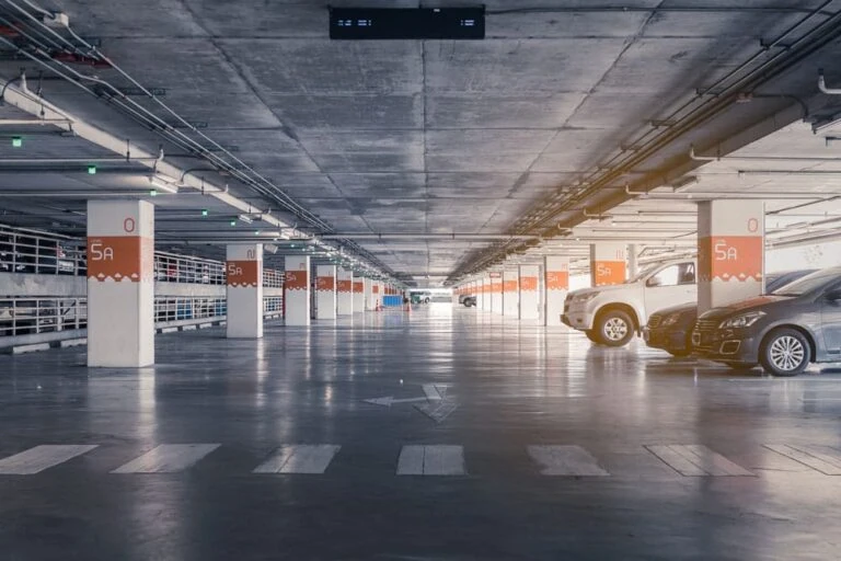 Interior of a parking garage with a few cars in an otherwise vacant parking lot