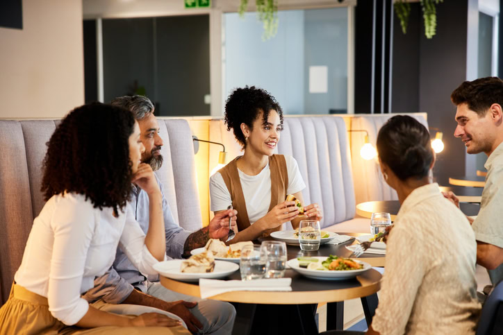 Smiling group of businesspeople talking together while having lunch