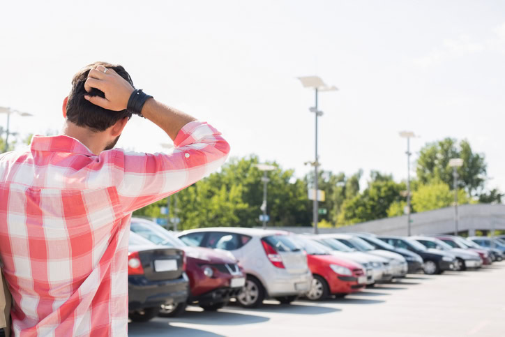 Man with hand behind head confused standing in parking lot