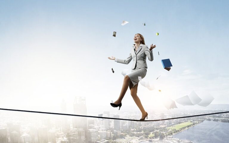 Young pretty businesswoman juggling business items while balancing on a tightrope over a city