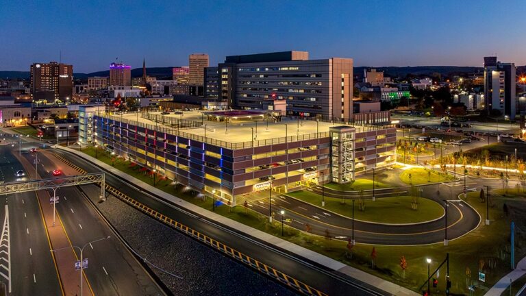 Lit parking garage at dusk near a highway in a large city