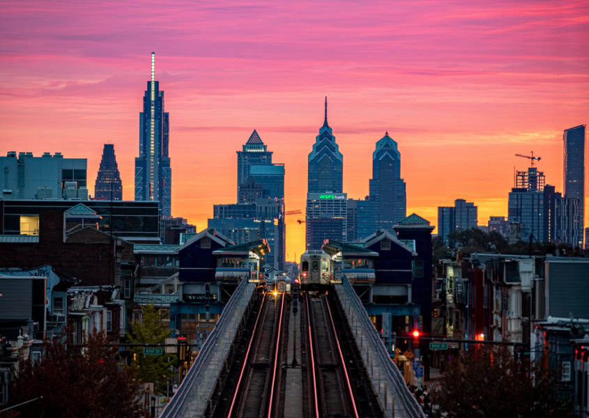 An aerial view of Benjamin Franklin Bridge and Philadelphia skyline on colorful sunset sky background
