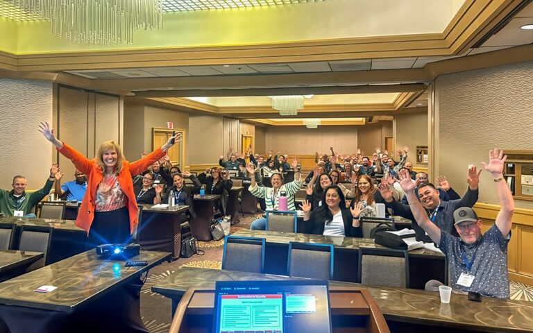 Conference attendees with their arms up in the air and happy faces