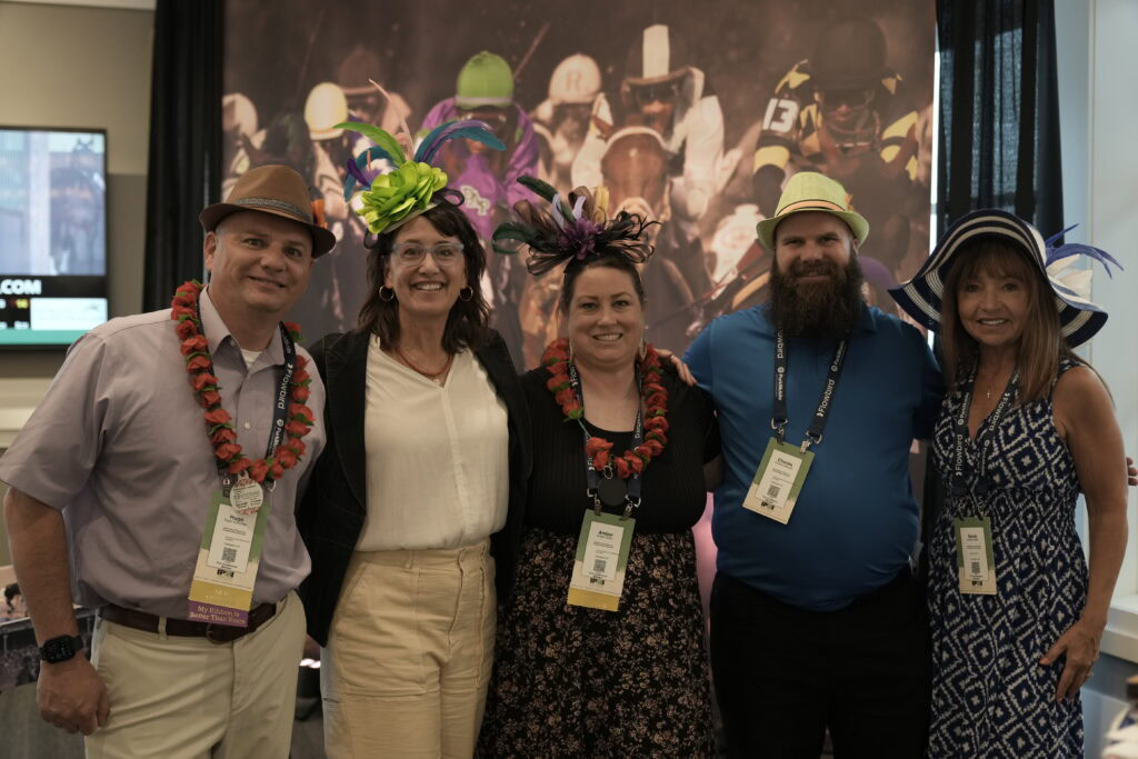 group of people wearing funny hats at a racetrack