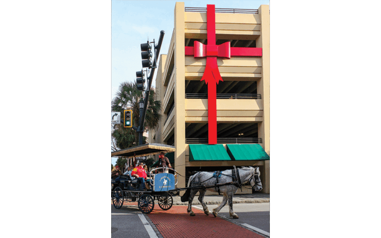 King Queen Street, with horse drawn sight-seeing tour in front of parking garage with big red bow