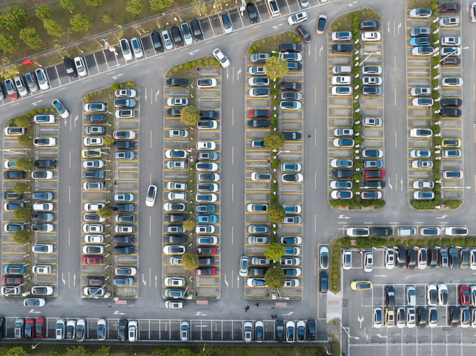 Bird's eye view of outdoor parking lot surrounded by greenery